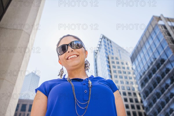 Hispanic woman walking under highrise buildings