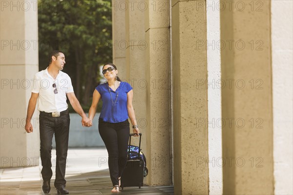 Hispanic couple holding hands under columns