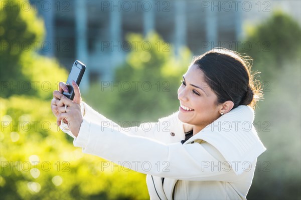 Hispanic woman taking selfie with cell phone