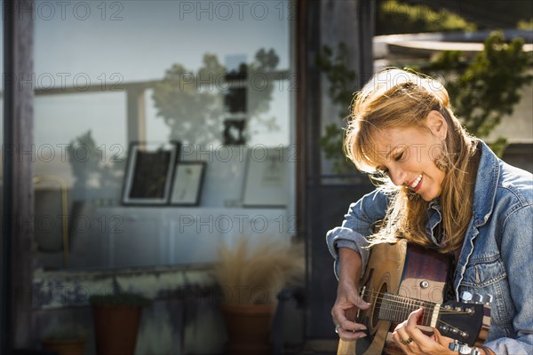 Caucasian woman playing guitar on porch