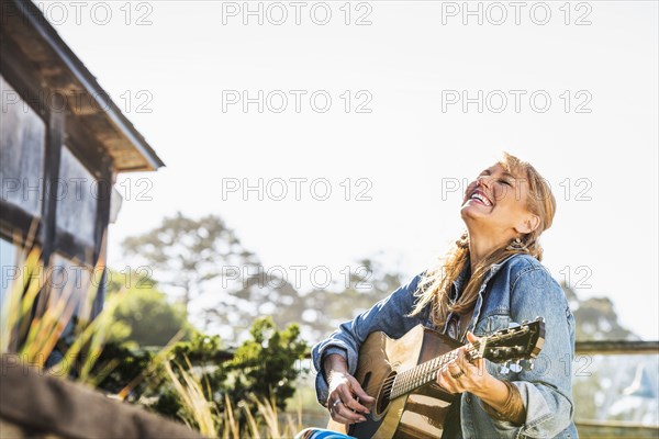 Caucasian woman playing guitar on porch