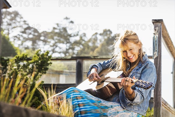 Caucasian woman playing guitar on porch