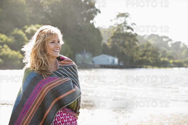 Caucasian woman wrapped in blanket on beach