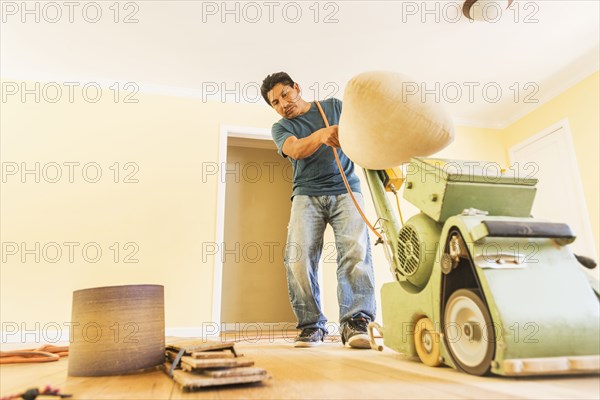 Hispanic man refinishing floors in new house