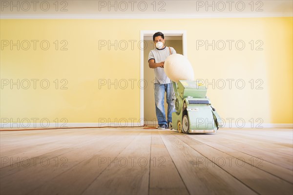 Hispanic man refinishing floors in new house