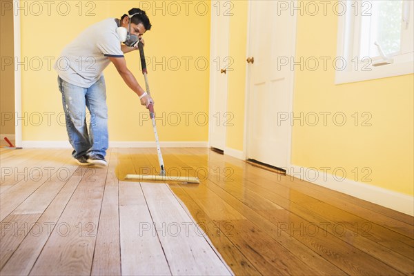 Hispanic man refinishing floors in new house