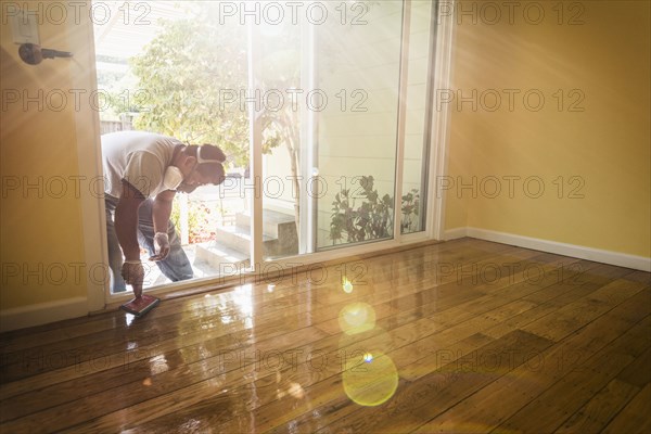 Hispanic man refinishing floors in new house