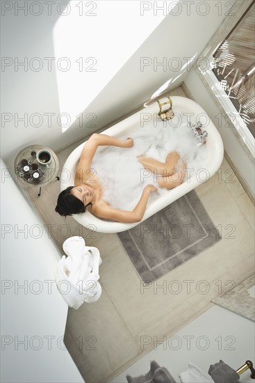 Woman having bubble bath in bathroom