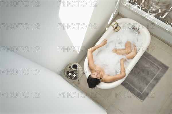 Woman having bubble bath in bathroom