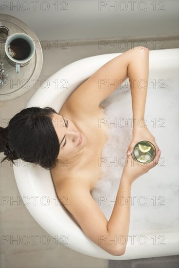 Woman drinking cocktail in bubble bath