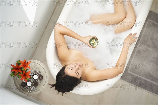 Woman drinking cocktail in bubble bath