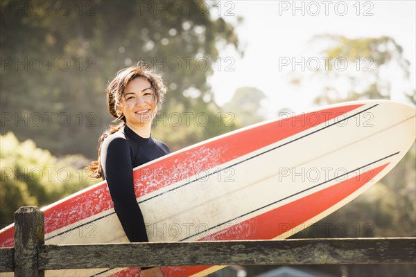 Woman carrying surfboard outdoors