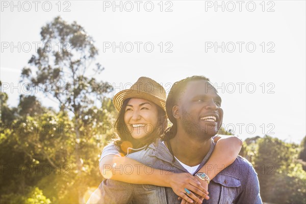 Man carrying girlfriend piggyback outdoors