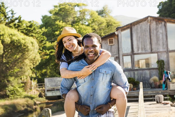 Man carrying girlfriend piggyback outdoors