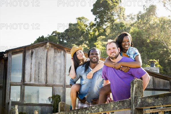 Men carrying girlfriends piggyback outdoors