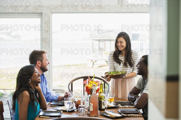 Woman serving friends at dinner party