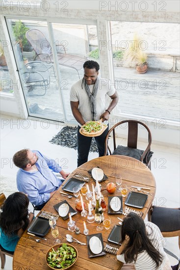 Man serving friends at dinner party