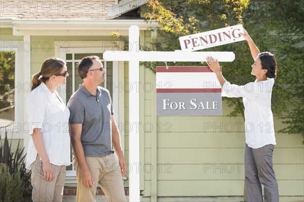 Real estate agent hanging sign outside house