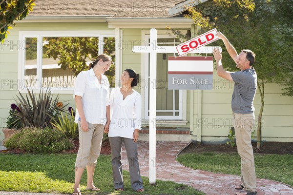 Real estate agent hanging sign outside house