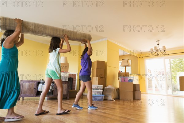 Children carrying carpet in new house