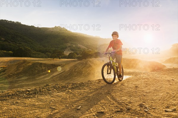 Mixed race boy riding dirt bike on track
