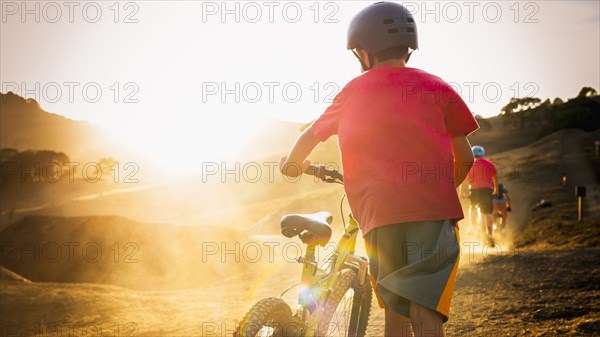 Mixed race boy riding dirt bike on track