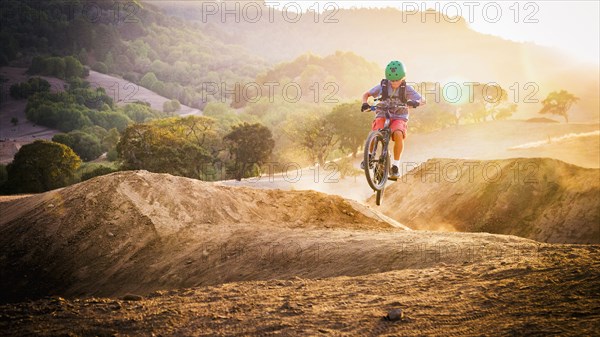 Mixed race boy riding dirt bike on track