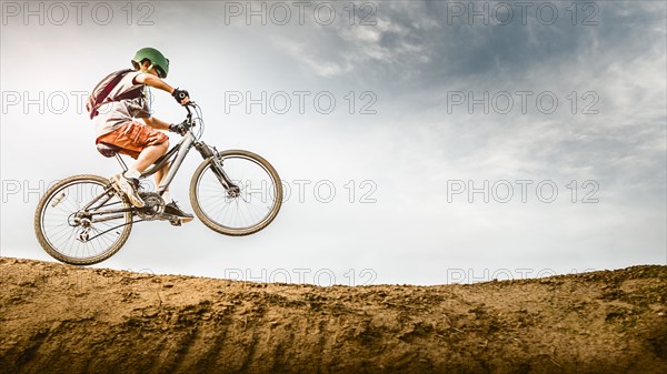 Mixed race boy riding dirt bike on track