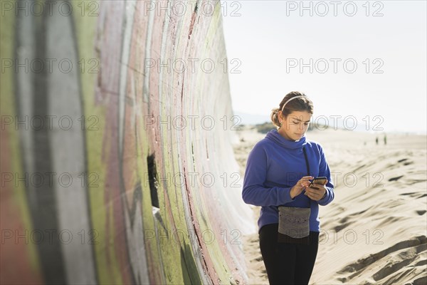 Mixed race girl using cell phone on beach