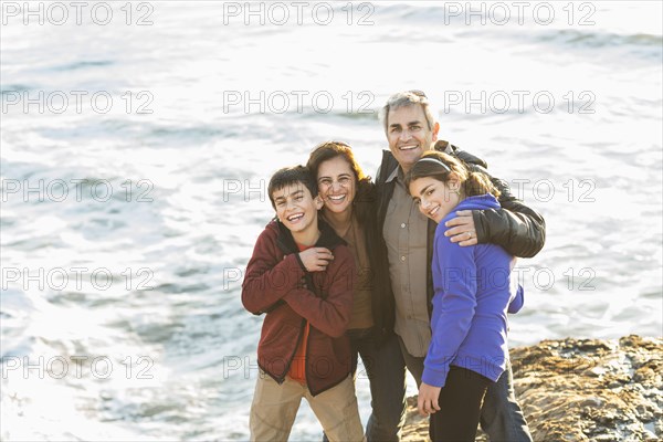 Family hugging near ocean waves