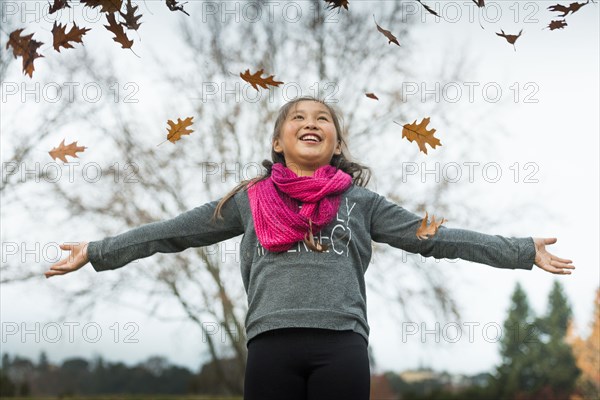 Mixed race girl playing in autumn leaves