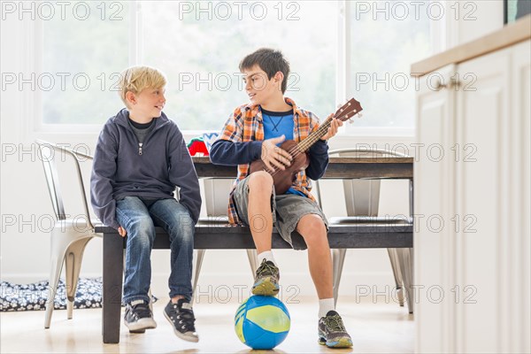 Boys siting on bench with ukulele and soccer ball