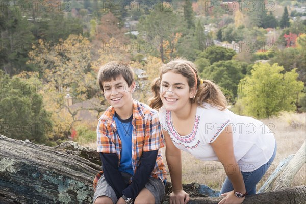 Mixed Race brother and sister posing on log