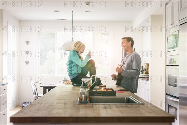 Caucasian girl using cell phone recording father playing guitar