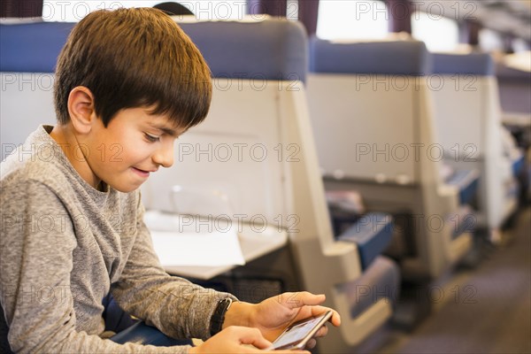 Mixed Race boy using cell phone on train