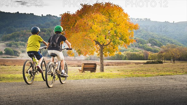 Mixed Race boys bike riding in park