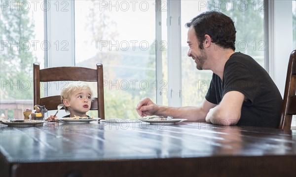 Caucasian father and son eating food at table