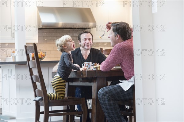 Caucasian father feeding son at table