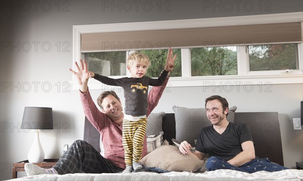 Caucasian fathers playing on bed with son