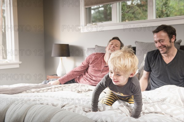 Caucasian fathers playing on bed with son