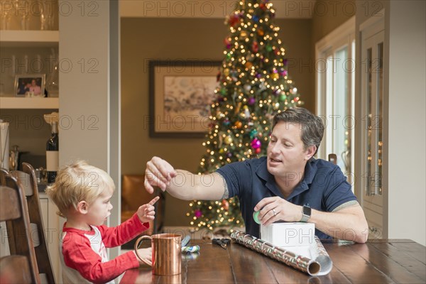 Caucasian fathers and son wrapping Christmas gift