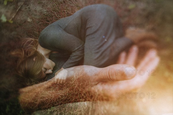 Double exposure of Caucasian woman laying in hand of man