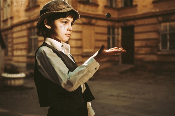 Caucasian boy wearing old-fashioned clothing tossing marble