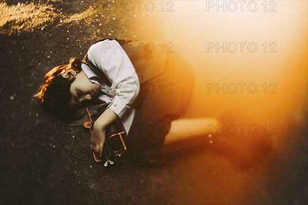 Old-fashioned Caucasian boy laying in street holding machinery