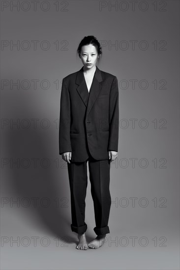 Barefoot Asian woman wearing large suit