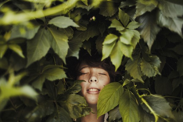 Caucasian boy smiling in leaves