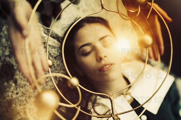 Hands holding metal circle over face of Caucasian woman