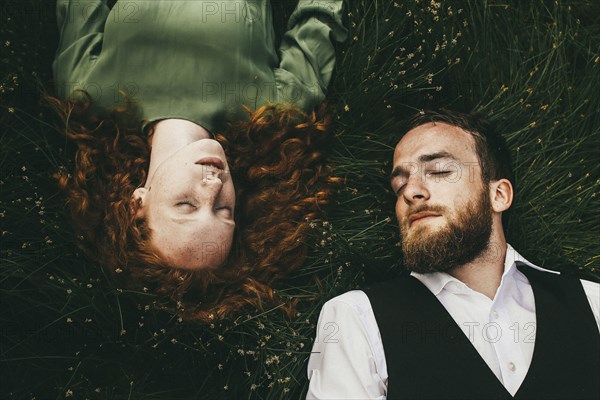 Caucasian couple laying in grass