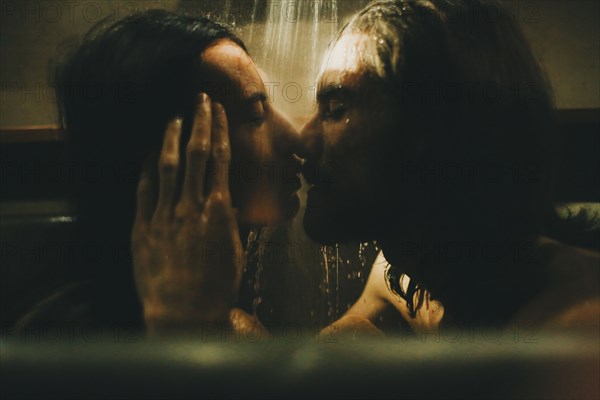 Caucasian couple relaxing in bathtub under shower