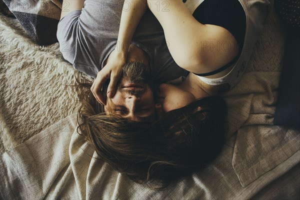 Caucasian couple cuddling with hair intertwined